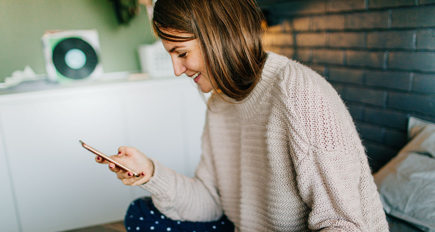 Frau schaut lächelnd auf ihr Smartphone