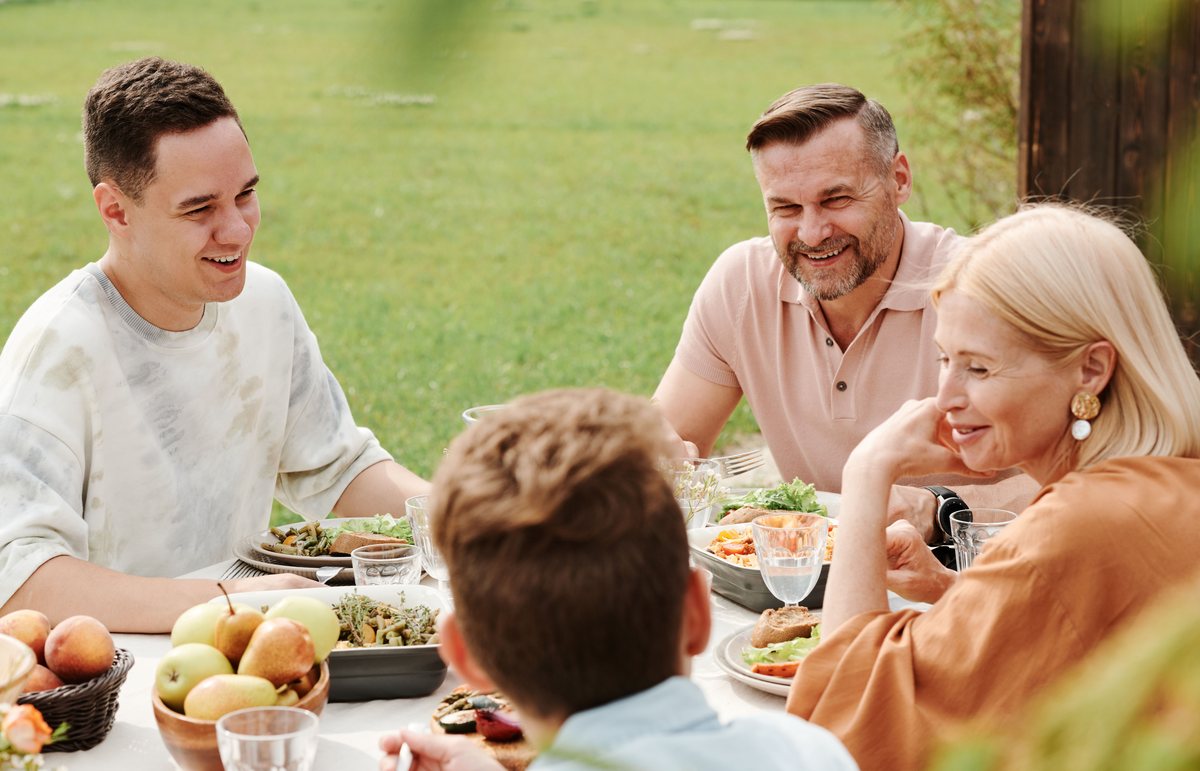 Familie sitzt dankbar an einem gedeckten Tisch im Garten
