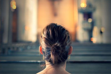 Frau, von hinten zu sehen, sitzt auf Kirchenbank. Joyce Meyer