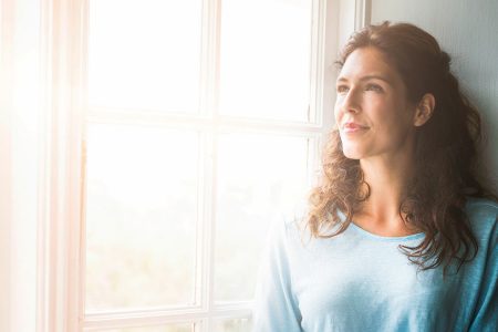 Frau sieht gelassen aus dem Fenster. Joyce Meyer