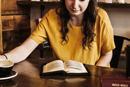 Frau, die ihre Bibel liest und Kaffee trinkt