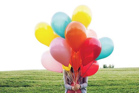 Frau hält mehrere bunte Luftballons in der Hand. Joyce Meyer
