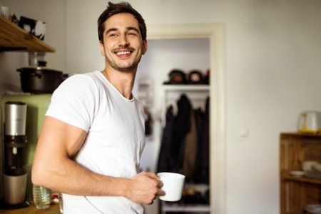 Mann mit Tasse in der Hand schaut lachend in die Ferne. Joyce Meyer